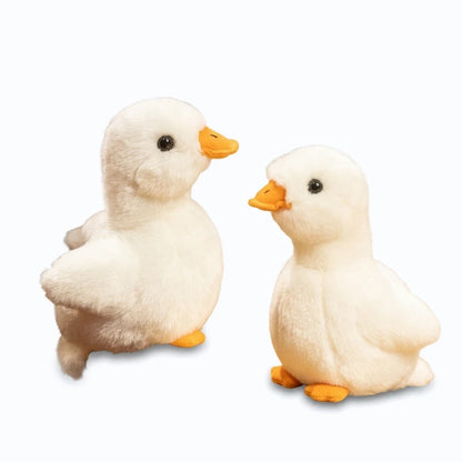 Petit canard blanc moelleux assis sur un lit, jouet peluche idéal pour les enfants