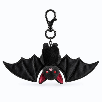 Porte clé doudou noir pelucheux accroché à un sac à dos