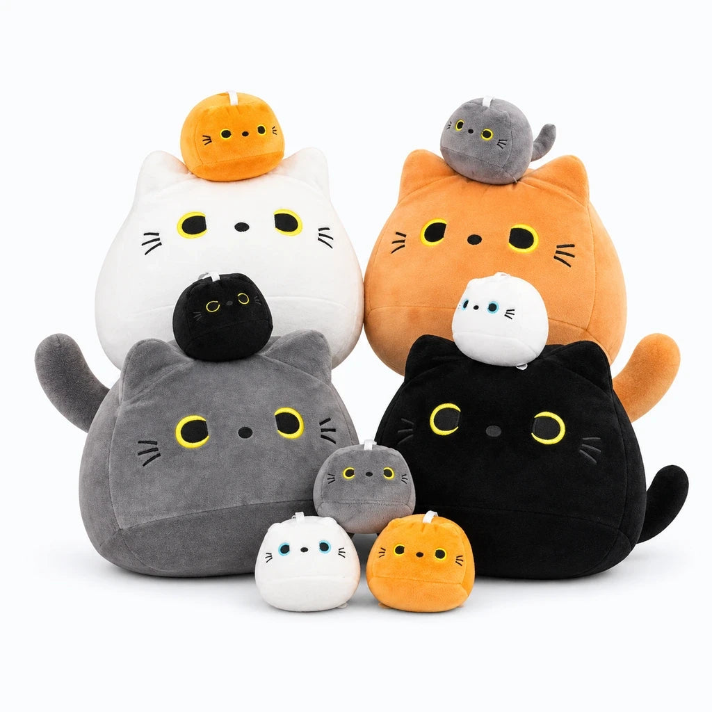 Chat en peluche noir posé sur un lit comme oreiller décoratif