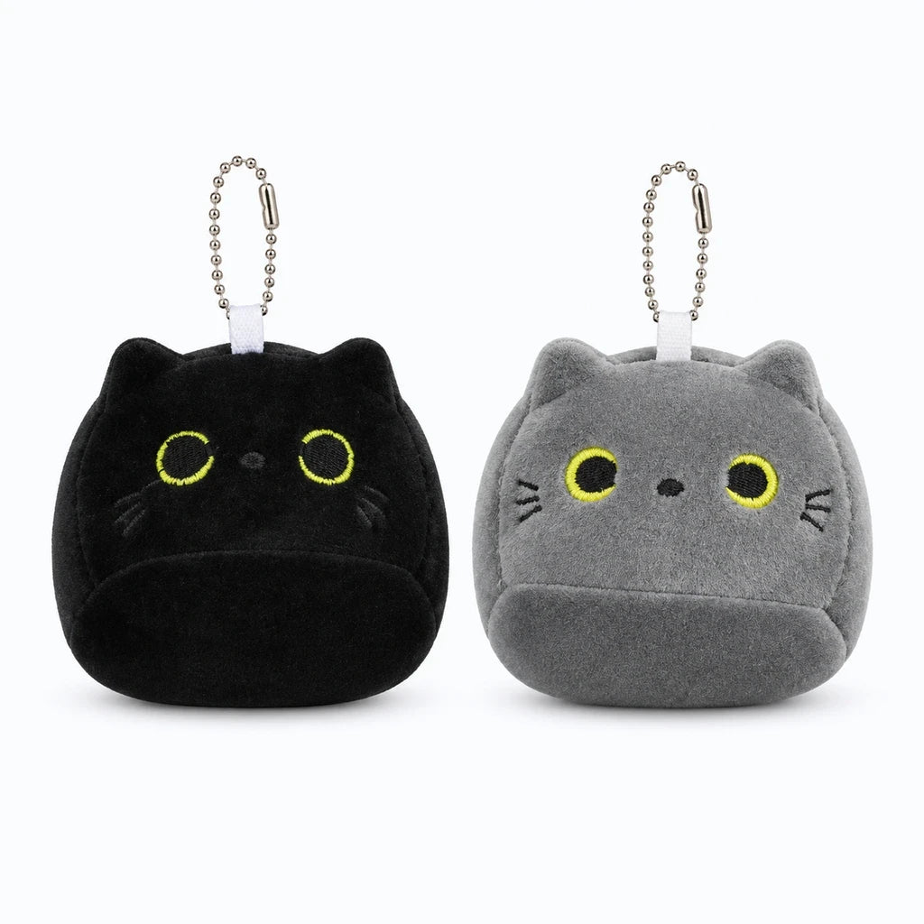 Petit chaton en peluche gris assis à côté de la maman chat noir